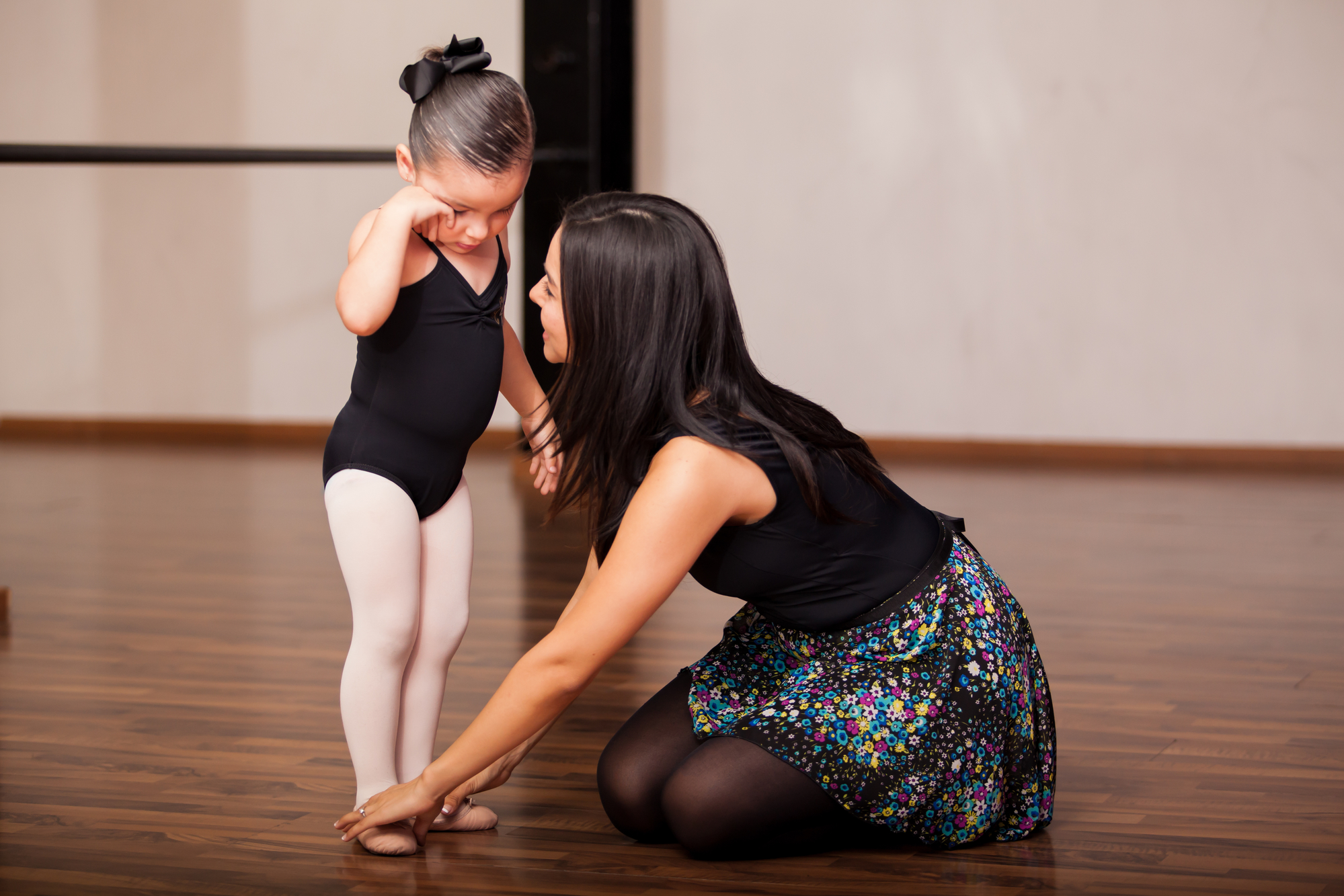 Няня-преподаватель балета помогает ученице