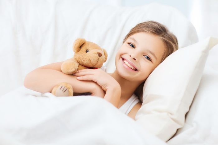 Девочка с игрушкой лежит в постели