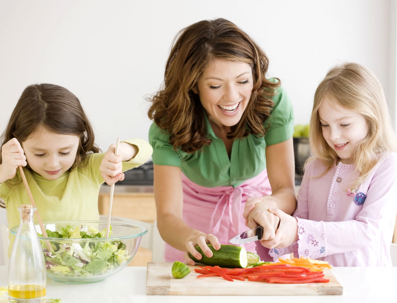 Няня помогает девочкам готовить салат